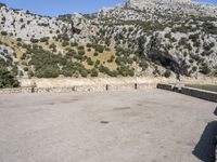 a building that is standing in the middle of the street with a rocky hill behind it