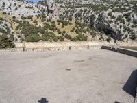 a building that is standing in the middle of the street with a rocky hill behind it