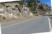 the winding highway is very steep and has a cliff side, with pine trees on each side