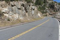 the winding highway is very steep and has a cliff side, with pine trees on each side