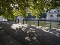 the long walkway passes through the trees by the riverbank and boats are floating on it