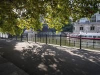 the long walkway passes through the trees by the riverbank and boats are floating on it