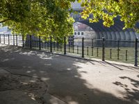 the long walkway passes through the trees by the riverbank and boats are floating on it