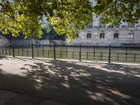 the long walkway passes through the trees by the riverbank and boats are floating on it