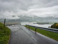 a winding road with a bridge on the side of it surrounded by mountains and water