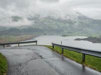 a winding road with a bridge on the side of it surrounded by mountains and water