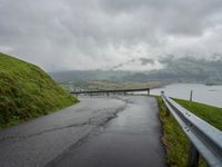 a winding road with a bridge on the side of it surrounded by mountains and water