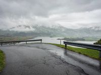 a winding road with a bridge on the side of it surrounded by mountains and water