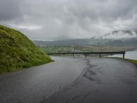 a winding road with a bridge on the side of it surrounded by mountains and water