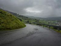a winding road with a bridge on the side of it surrounded by mountains and water