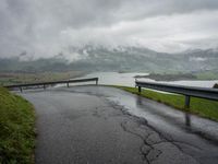 a winding road with a bridge on the side of it surrounded by mountains and water