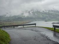 a winding road with a bridge on the side of it surrounded by mountains and water