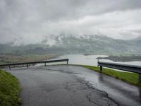 a winding road with a bridge on the side of it surrounded by mountains and water