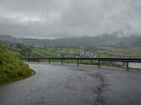 a winding road with a bridge on the side of it surrounded by mountains and water