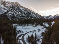 a scenic winding road in the mountains during the day time or the evening sun on a snowy day