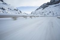 the car travels along the mountainous road on snowy day - like terrain, driving through snow - covered mountains and forest