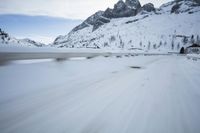 the car travels along the mountainous road on snowy day - like terrain, driving through snow - covered mountains and forest