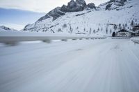 the car travels along the mountainous road on snowy day - like terrain, driving through snow - covered mountains and forest