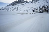 the car travels along the mountainous road on snowy day - like terrain, driving through snow - covered mountains and forest
