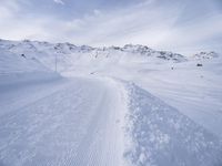 snow covered slope in the middle of a ski area as people ski on it near ski lift