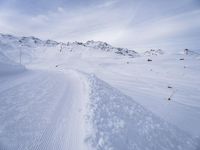 snow covered slope in the middle of a ski area as people ski on it near ski lift