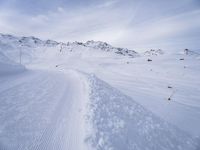 snow covered slope in the middle of a ski area as people ski on it near ski lift