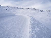 snow covered slope in the middle of a ski area as people ski on it near ski lift