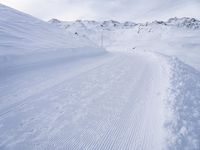 snow covered slope in the middle of a ski area as people ski on it near ski lift