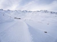 snow covered slope in the middle of a ski area as people ski on it near ski lift