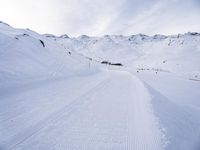 snow covered slope in the middle of a ski area as people ski on it near ski lift