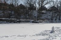 a man is skiing in the snow outside by some buildings and trees of course hill