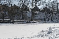 a man is skiing in the snow outside by some buildings and trees of course hill