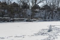 a man is skiing in the snow outside by some buildings and trees of course hill