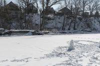 a man is skiing in the snow outside by some buildings and trees of course hill