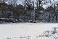 a man is skiing in the snow outside by some buildings and trees of course hill