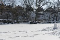 a man is skiing in the snow outside by some buildings and trees of course hill