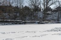 a man is skiing in the snow outside by some buildings and trees of course hill