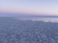 a view of an ice covered lake and the sky on a clear day at dusk