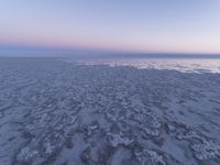 a view of an ice covered lake and the sky on a clear day at dusk