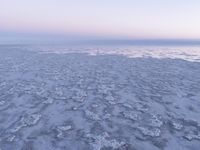 a view of an ice covered lake and the sky on a clear day at dusk