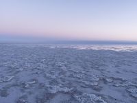 a view of an ice covered lake and the sky on a clear day at dusk