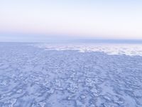 a view of an ice covered lake and the sky on a clear day at dusk