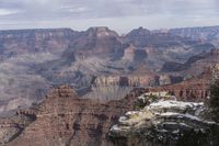 a scenic view of the grand canyon in winter time, with snow on the rocks and rocks