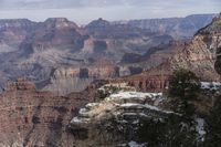 a scenic view of the grand canyon in winter time, with snow on the rocks and rocks