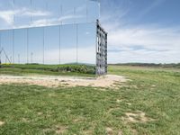 the large mirrored cube in a field is a unique sight to see it as if not in a mirror