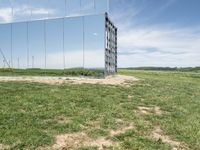 the large mirrored cube in a field is a unique sight to see it as if not in a mirror