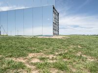 the large mirrored cube in a field is a unique sight to see it as if not in a mirror