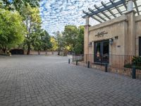 the entrance to an apartment building with brick pavers and an open patio area for entertaining people