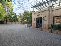 the entrance to an apartment building with brick pavers and an open patio area for entertaining people