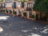 a cobblestone road lined with trees and buildings in an apartment complex courtyard area